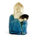 A porcelain water dropper,19th century, in the form of a literatus in blue robes, seated with his