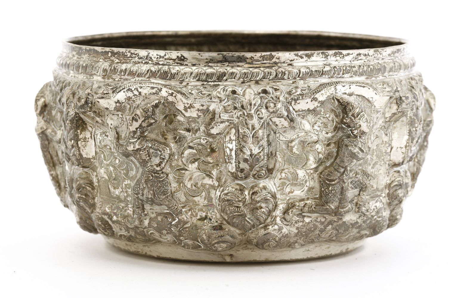 A Thai silver bowl,19th century, decorated in relief with dancing figures between columns, under