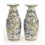 A pair of Chinese Canton enamelled vases,19th century, each painted with figures at a buffet in a