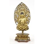 A Japanese gilt lacquered wood Buddha, Meiji period (1868-1912), seated cross-legged on a seedpod in