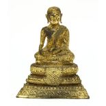 A Burmese gilt bronze Buddha,late 19th century, seated cross-legged on a stepped gilded and red