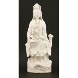 A Chinese blanc de Chine figure,18th century, of a Guanyin seated on a rock, scrolls by her side and