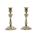 A pair of Continental white metal and filled candlesticks, 20th century, with cast scrolling stems