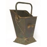 A copper coal scuttle, with riveted panels and embossed with a stylised pomegranate, with a swing