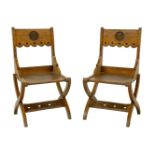 A pair of oak hall chairs,each with a central panel carved with an 'S', a solid seat and a pierced