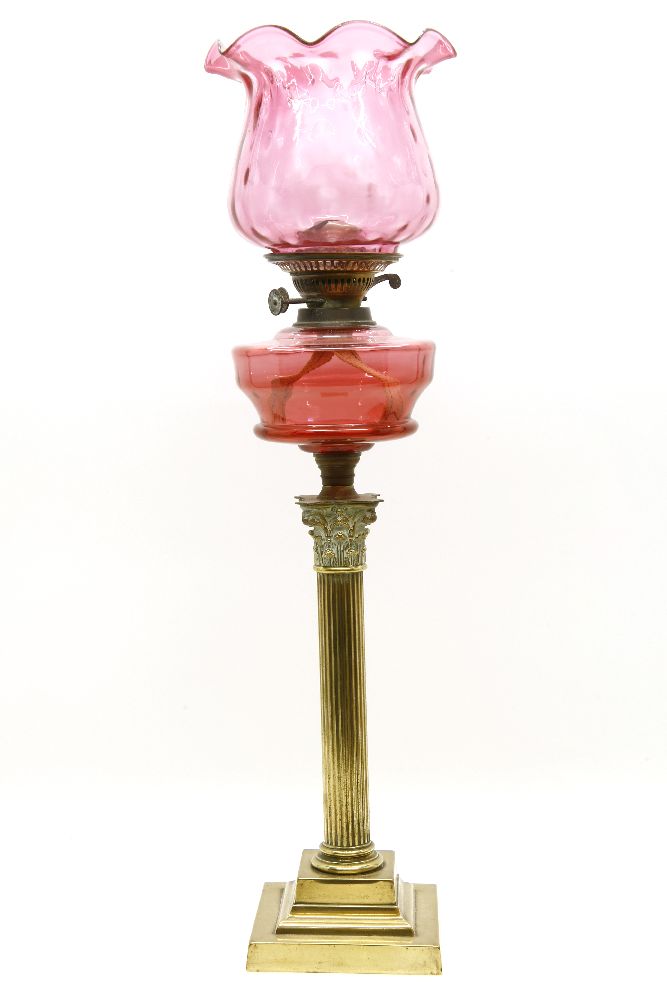 A brass oil lamp, with cranberry reservoir and shade, 80cm high to top of chimney