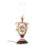 A twin handled vase form porcelain table lamp, the pink ground with landscape decorated reserve,