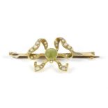 An Edwardian gold circular cut peridot and seed pearl bow brooch, (tested as approximately 14ct
