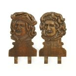 A pair of carved oak pediments,one in the form of Teniers, the other, Raphael, each 58cm high (2)