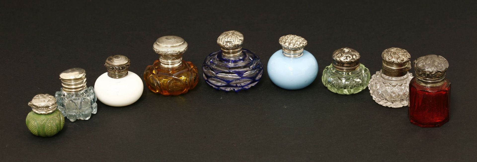 Nine small glass bottles with plated and silver mounts,with cut glass bases, 3.5cm largest (9)