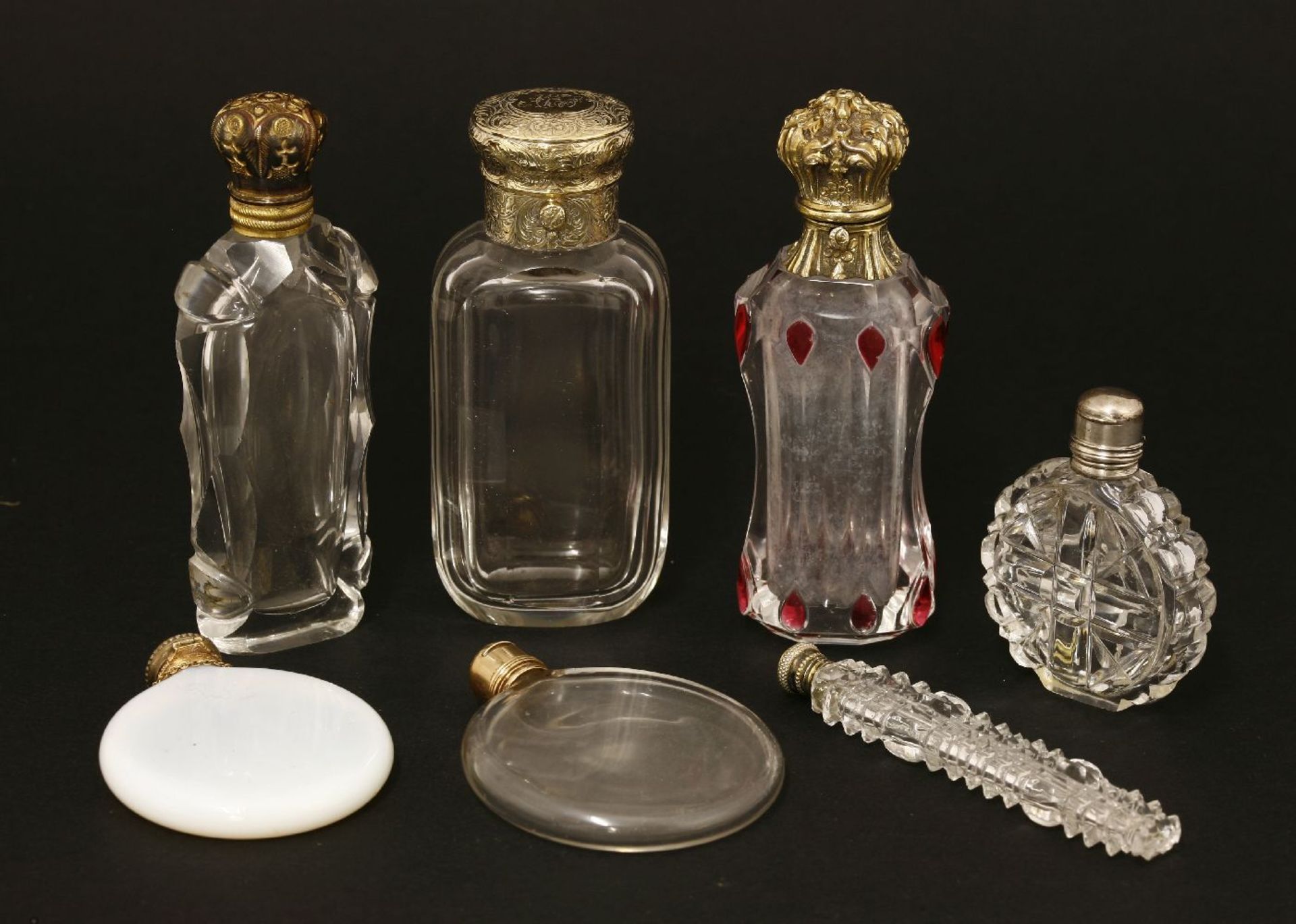 Seven glass scent bottles,late 19th/early 20th century, with white and gilt metal covers,largest