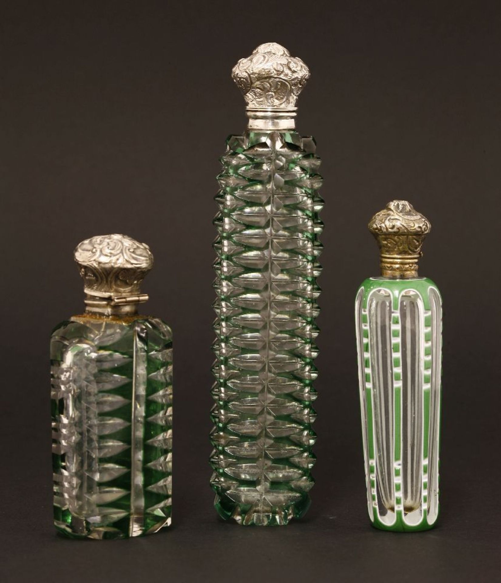 Three Bohemian clear glass scent bottles,19th century, two cased in green with cut decoration