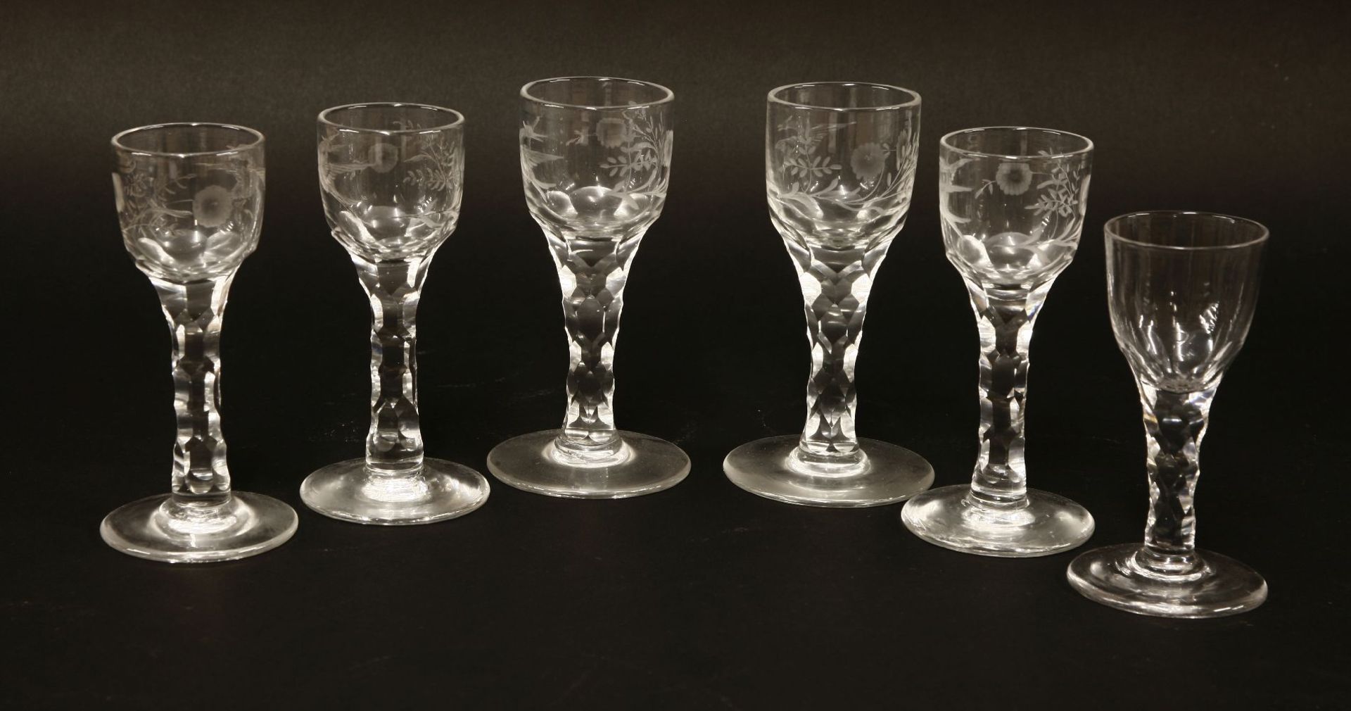 Six George III wine glasses,with facet cut stems, five with engraved ogee bowls, one plain,tallest