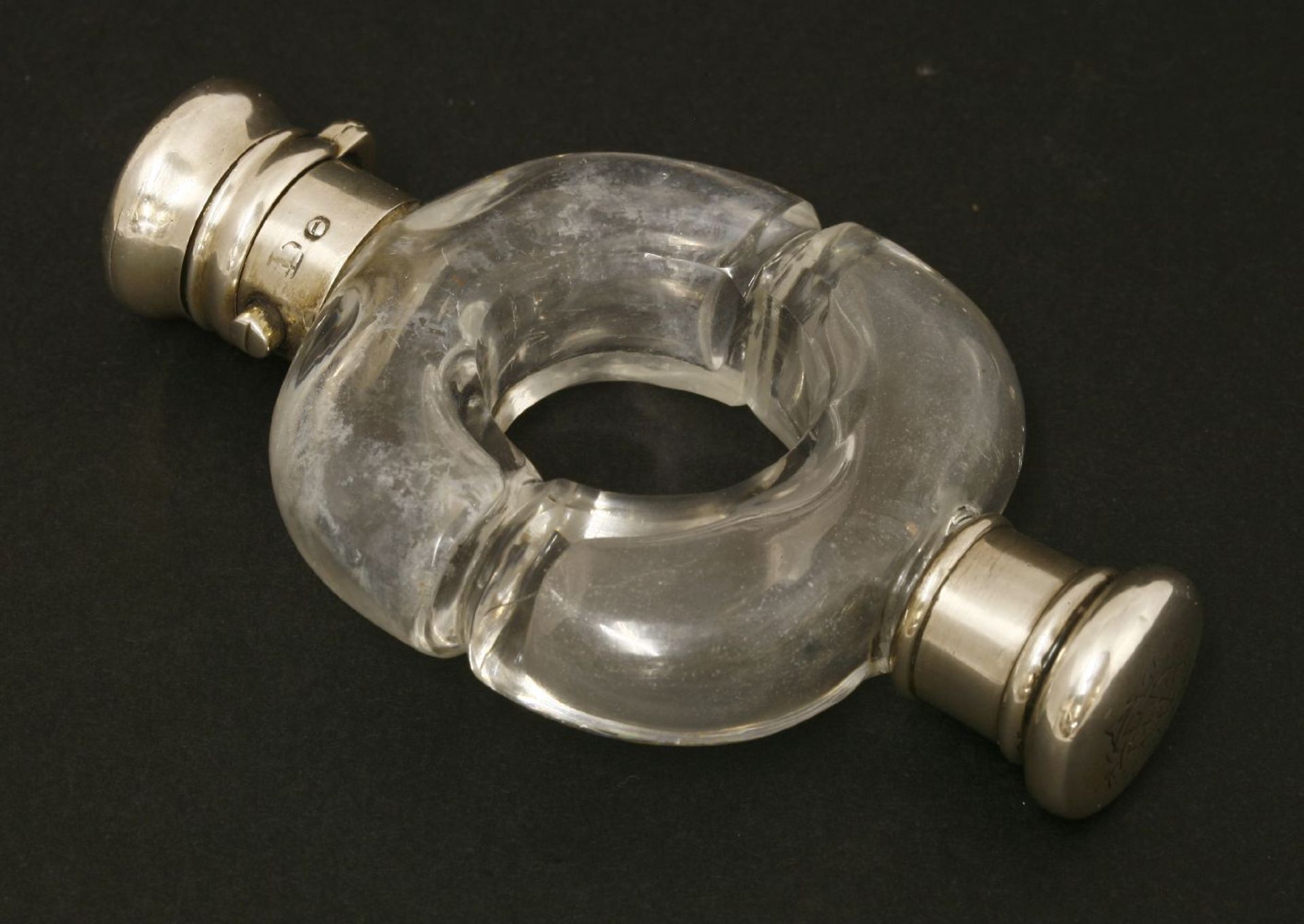 A clear glass scent bottle of ring form,19th century, the moulded body with two white metal