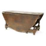 A massive eight-seat oak gateleg table,17th century, the oval drop-leaf top over two frieze drawers,