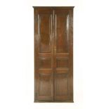 A George III oak standing corner cabinet,with two panelled full length doors enclosing shaped