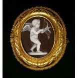A Victorian gold Etruscan Revival shell cameo brooch, c.1870,depicting Cupid. An oval carved shell