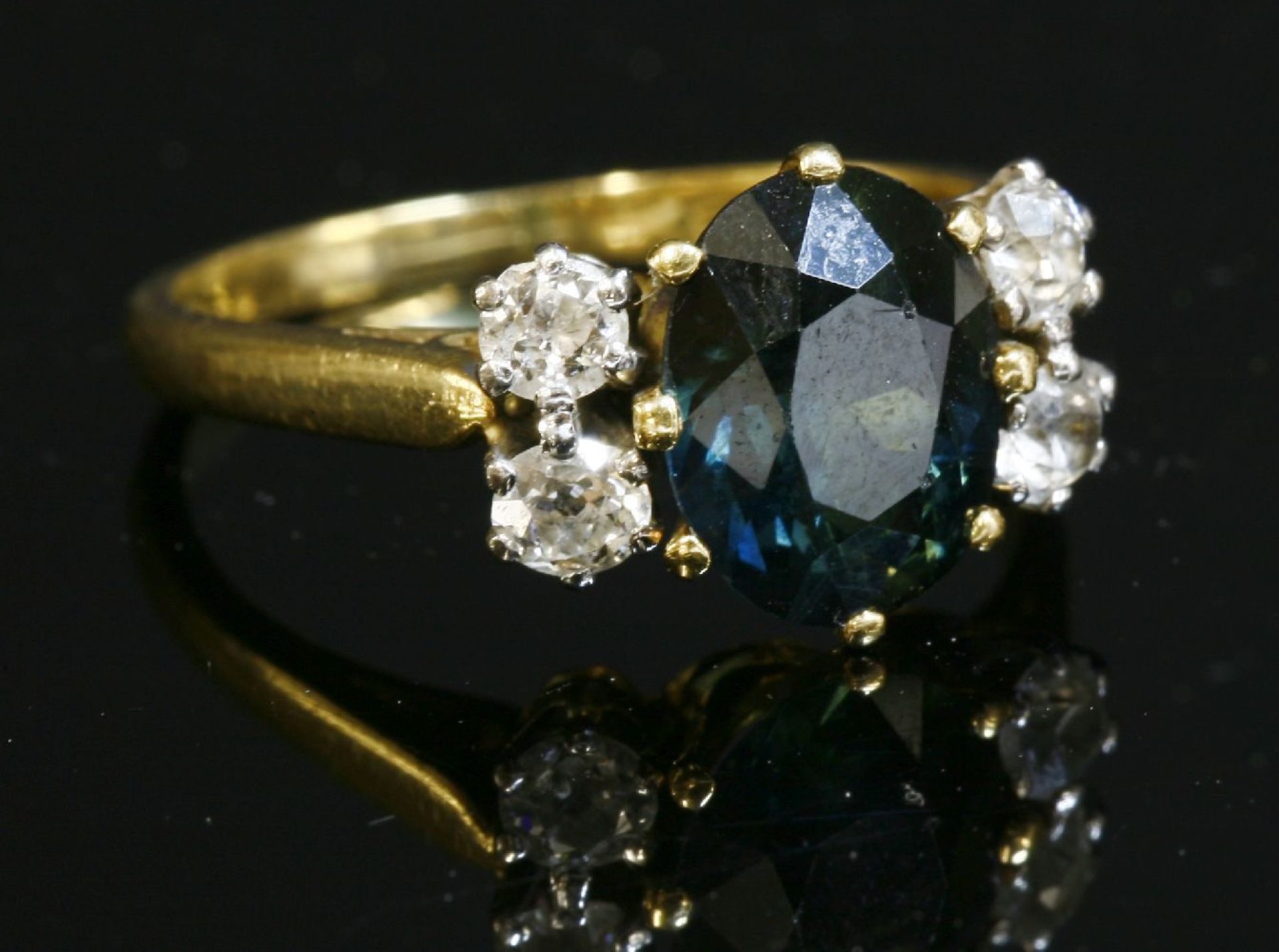 A green sapphire and diamond ring,with an oval mixed cut sapphire, claw set to the centre in a