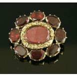 A garnet set gold memorial brooch, c.1830,with an oval glazed centre with a chased border. An