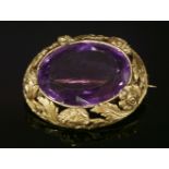 An early Victorian gold amethyst brooch,with an oval mixed cut amethyst, rub set to the centre. An