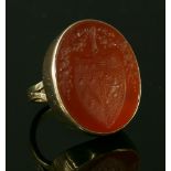 A gold intaglio carved cornelian ring,with an oval cabochon tablet intaglio entwined with a coat