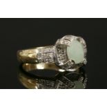 A 9ct gold jade cabochon and diamond cluster ring,with three-row diamond set shoulders. 4.75g.Finger