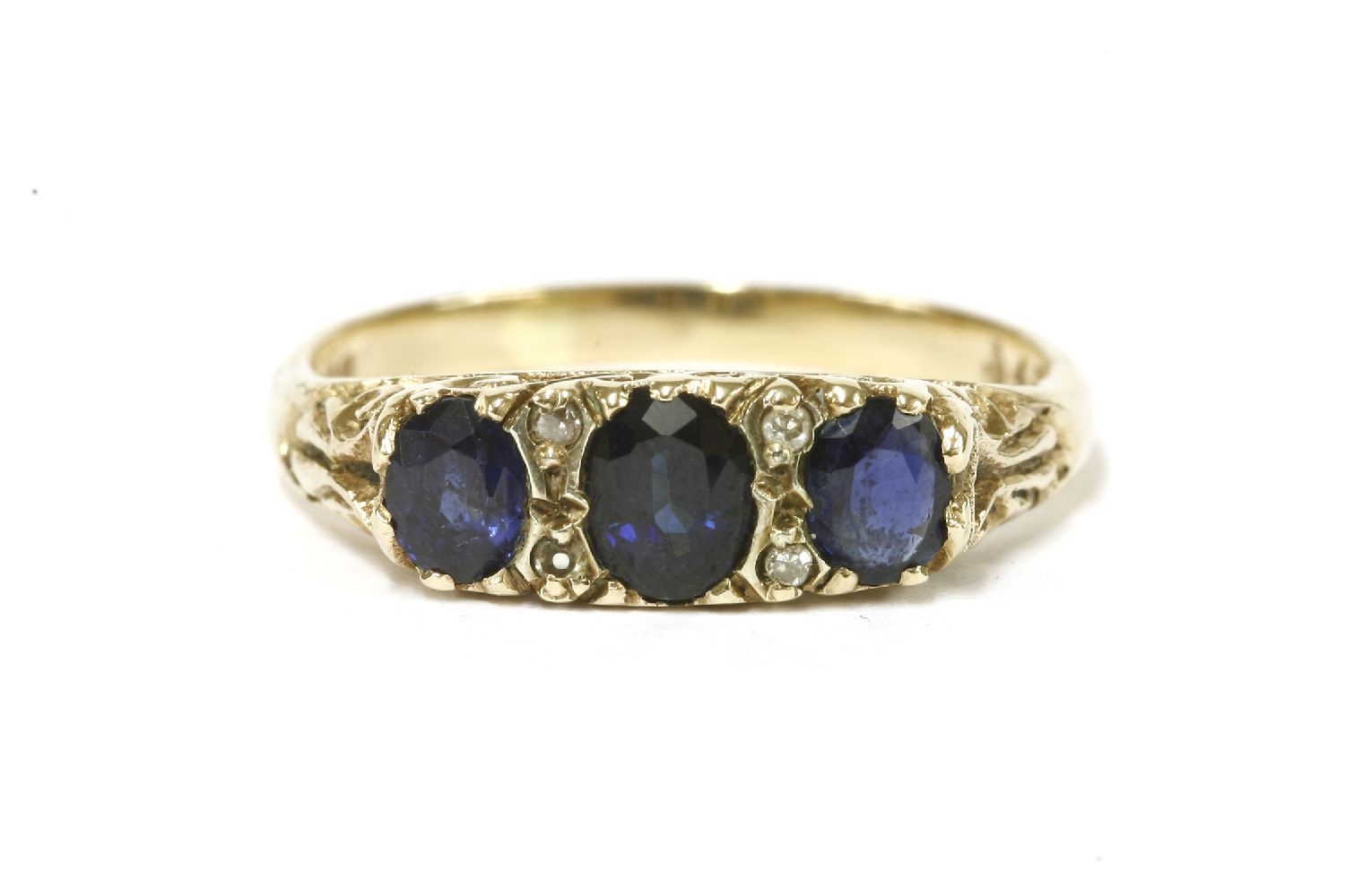 A 9ct three stone graduated sapphire ring, with diamond set points to scrolling shoulders and a