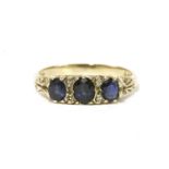 A 9ct three stone graduated sapphire ring, with diamond set points to scrolling shoulders and a