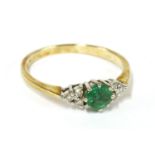 An 18ct gold circular cut emerald ring, flanked with trefoil clusters of diamonds, size N2.27g