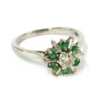 An 18ct white gold diamond and emerald star burst cluster ring, with baguette cut diamond rays to