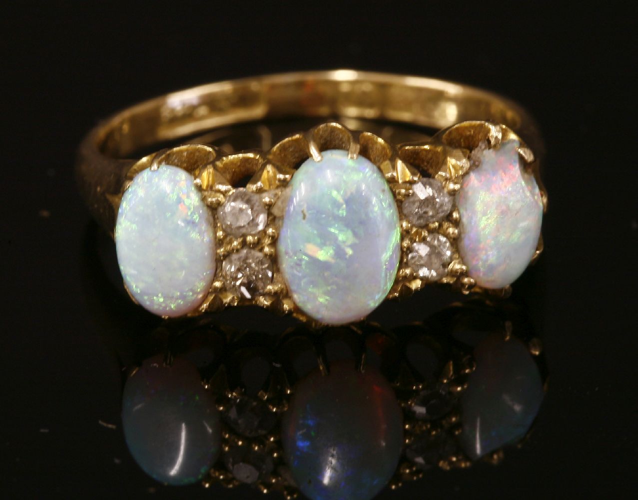 An 18ct gold Edwardian opal and diamond ring,with three graduated oval cabochon opals, all claw