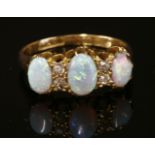 An 18ct gold Edwardian opal and diamond ring,with three graduated oval cabochon opals, all claw