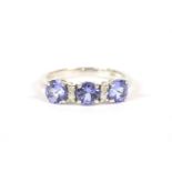 A 9ct white gold three stone tanzanite ring with pairs of diamonds between, 2.53g