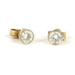 A pair of 18ct gold single stone diamond stud earrings, rub set to a white setting edge, to a yellow