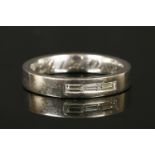 An 18ct white gold three stone baguette cut diamond wedding ring, engraved to interior 'M&M, 13th