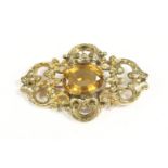 A Victorian single stone citrine brooch, oval cut citrine, rub set to a scrolling surround (tested