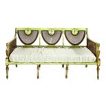 A late 19th century French green painted three-seat settee, having a cane back, arms and seat, on