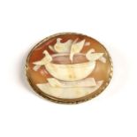 A gold mounted gold shell cameo brooch, carved, depicting doves drinking from a bowl, (tested as