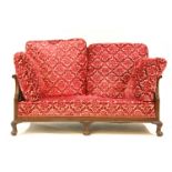 A Regency style bergere settee, the caned back and arms over carved cabriole legs and claw and