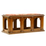 A large Gothic revival oak hall seat, the pad seat upholstered top over arched sides and plinth