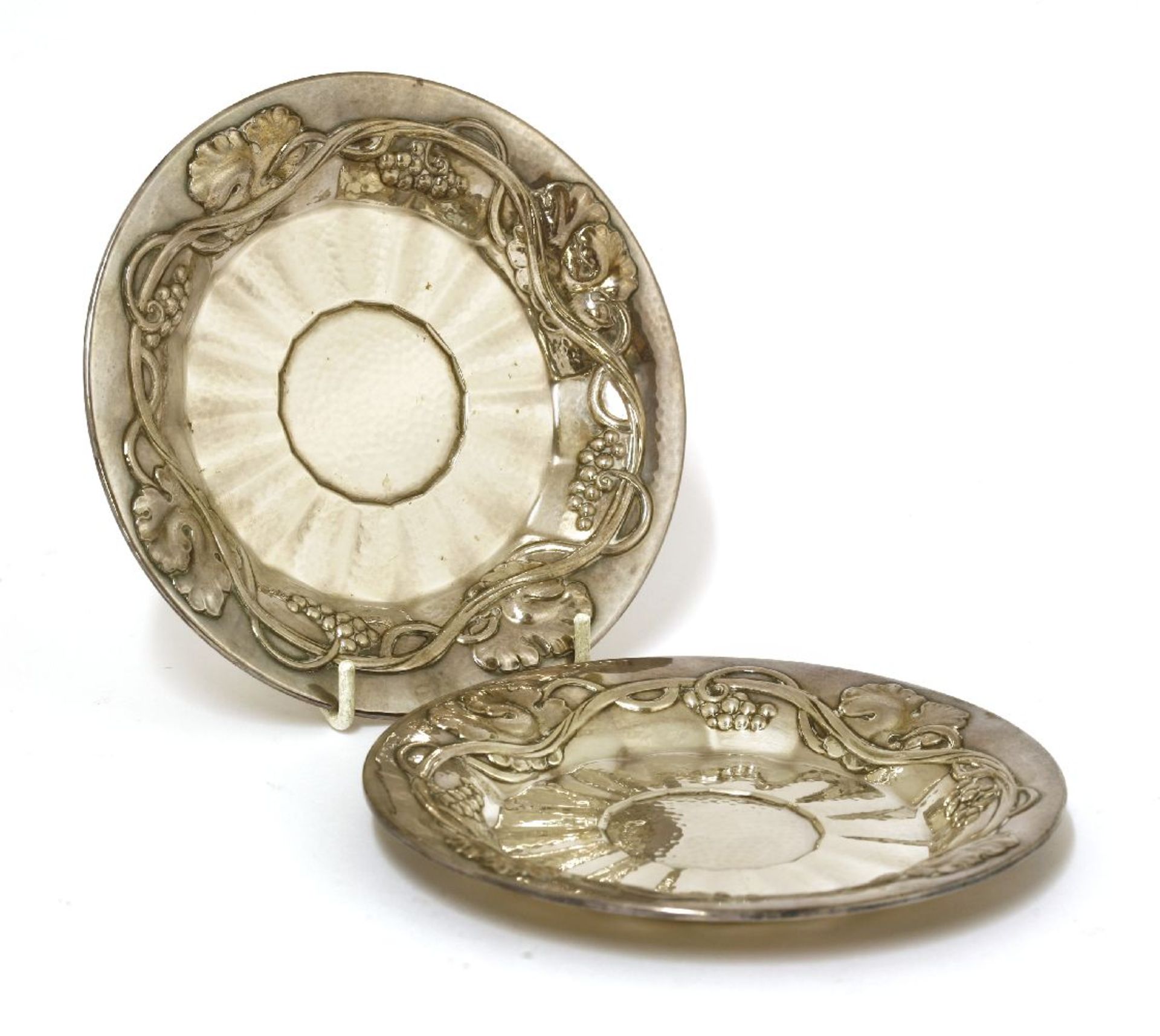 A pair of Georg Jensen silver dishes, each with a fruiting vine border around a hammered centre,