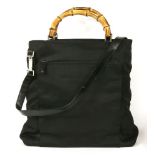 A Gucci black canvas cross-body handbag, featuring the maker's curved rigid bamboo handle,