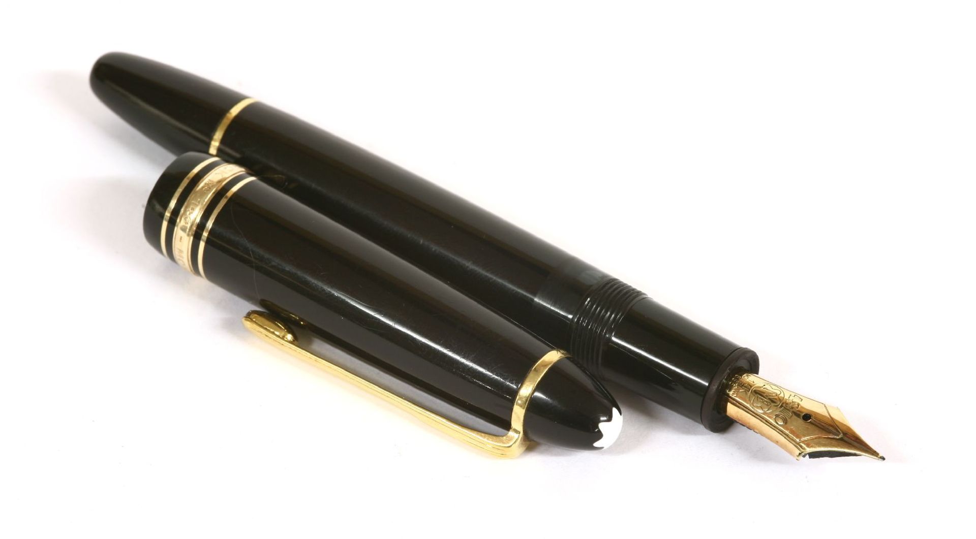 A Mont Blanc Meisterstück fountain pen,with a black barrel and cap, gold-plated banding and clip,