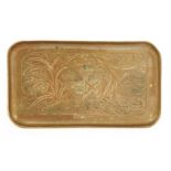 A copper tray,embossed with a central shield flanked with scrollwork, over a banner with an