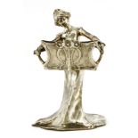 An Art Nouveau silvered centrepiece, in the form of a lady in a flowing dress, holding a basket,