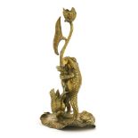A brass candlestick,modelled as frogs standing on a lily pad, holding a flower that forms the candle