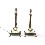 A near pair of bronzed and gilded table lamps, with foliate capitals and stylised foliage on a white