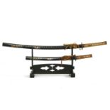 A reproduction Japanese katana and wakizashi on a black lacquer stand