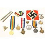 A WWII Nazi arm band, two sets of WWI medals, and other badges