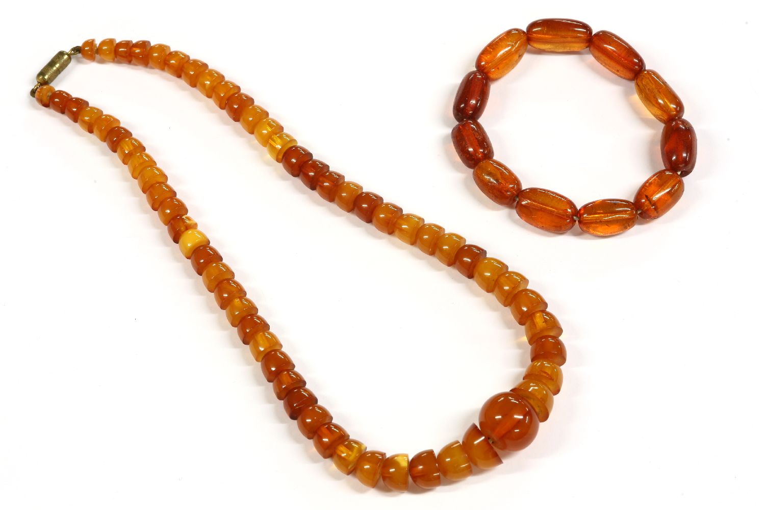 An Art Deco single row graduated half bead shaped amber bead necklace, with central circular bead,